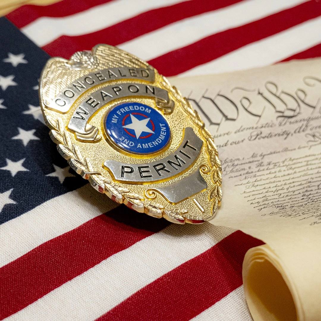 Concealed weapon permit badge resting on an American flag and the Constitution